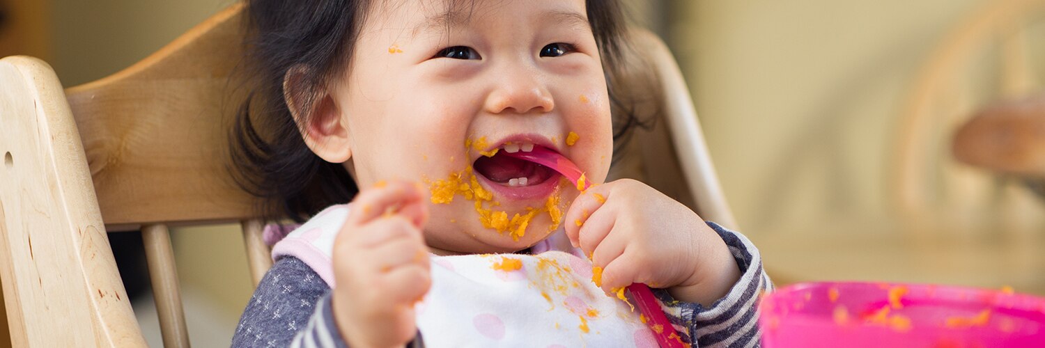Smiling Toddler While Eating Mobile