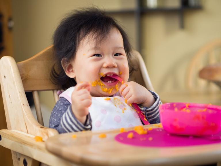 Smiling Toddler While Eating Mobile
